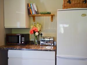 eine Küchentheke mit einer Mikrowelle und einer Vase aus Blumen in der Unterkunft Cowbeech Farm Cottage in Herstmonceux