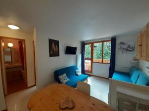 un salon avec une table et un canapé bleu dans l'établissement Appartement 2 pièces proche télécabine, 4 personnes, parking gratuit - FR-1-561-145, à Valfréjus