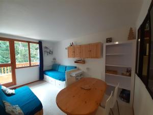 une petite pièce avec une table et un canapé bleu dans l'établissement Appartement 2 pièces proche télécabine, 4 personnes, parking gratuit - FR-1-561-145, à Valfréjus