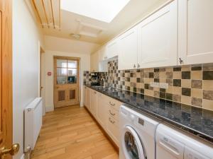 una cucina con mobili bianchi, lavatrice e asciugatrice di Winton Cottage - Uk50380 a Pencaitland Altre 19 foto