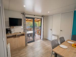 a living room with a dining table and a television at Mobil home 32m² avec terrasse, 3 chambres pour 6 personnes - API-1-52-713 in Barbey-Séroux