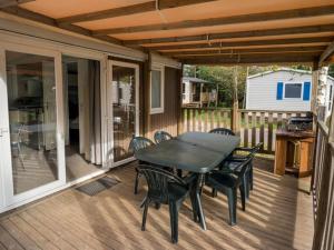 een terras met een tafel en stoelen op een dek bij Mobil home avec terrasse au camping à Granges-Aumontzey - API-1-52-299 in Barbey-Séroux
