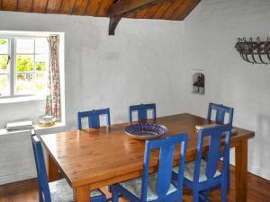 ein Esstisch aus Holz mit vier blauen Stühlen in der Unterkunft Cider Cottage - Uk50076 in Sidmouth