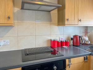 a kitchen with a stove with red cups on it at Rosie's Cottage in Bridlington