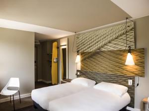 ワーヴルにあるIbis Wavre Brussels Eastのベッドルーム1室(白いベッド2台付)と黄色い壁が備わります。