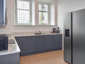 a kitchen with gray cabinets and a sink and two windows at Former Methodist Church - Uk49641 in Airton