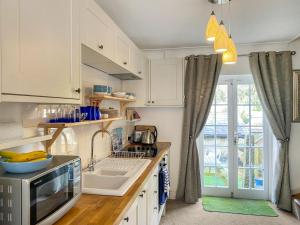 una cucina con mobili bianchi e un lavandino di Issys Cottage a Helston
