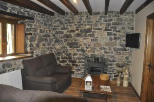 a living room with a couch and a stone wall at Casa La Ribera in Lon