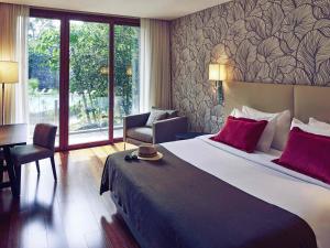 a bedroom with a large bed with red pillows at Mercure Iguazu Hotel Iru in Puerto Iguazú