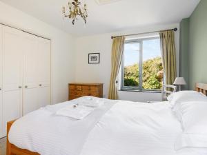 a bedroom with a white bed and a window at The Roost in Saint Breward +12 photos