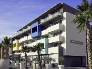 Un edificio con palmeras delante. en Mercure Hotel Golf Cap d'Agde, en Cap d'Agde