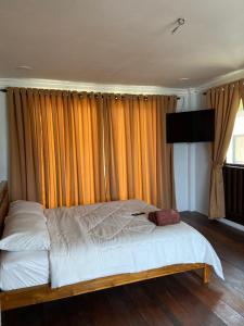 a bed in a bedroom with curtains and a television at Rumah Sungai Impiana PCB Room 7 in Gua Sai