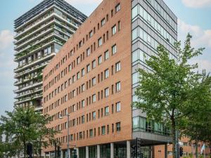 un edificio alto de ladrillo con árboles delante de él en Mercure Amsterdam Sloterdijk Station, en Ámsterdam