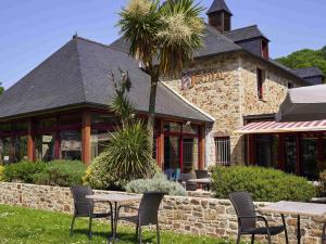 a restaurant with tables and chairs in front of a building at Mercure Dinan Port Le Jerzual in Dinan