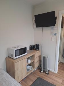 a room with a microwave and a tv on the wall at TuiHideaway cozy studio sleepout in Mount Maunganui