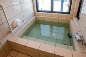 a bathroom with a bath tub with a window at 民宿かまだ MinshukuKamada in Hatsukaichi +3 photos