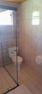 a bathroom with a toilet and a glass door at Chalé Sonho Diniz 3 in Monte Verde +53 photos