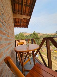 a wooden table and chairs on a balcony at Chalé Sonho Diniz 3 in Monte Verde