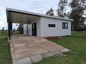 a white building with its door open in a field at Chacra Lavanda Casas de Campo, 3 dormitorios in Salto