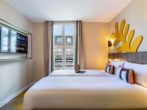 a large white bed in a room with a window at Ibis Styles Paris Jardin de la Villette - Rénové en 2025 in Paris