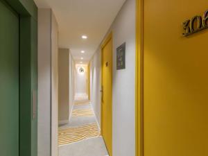 a hallway with yellow and green walls at Ibis Styles Paris Jardin de la Villette - Rénové en 2025 in Paris