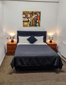 a bedroom with a blue bed with two night stands at Kiwi As Guest House in Rotorua