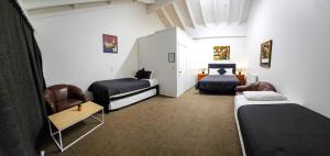 a room with two beds and two chairs in it at Kiwi As Guest House in Rotorua