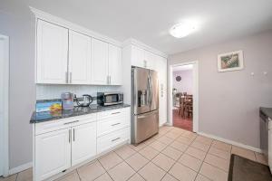 Una cocina con gabinetes blancos y un refrigerador de acero inoxidable. en Dreamy Garden Arch Spot Cozy 3Bedroom Villa near the Beach, en Surrey