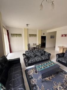 a living room with black couches and a table at Cameron Prima Villa Homestay in Tanah Rata
