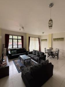 a living room with black couches and a table at Cameron Prima Villa Homestay in Tanah Rata