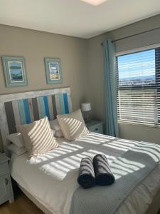 a bedroom with a bed with two pairs of shoes on it at Sunset at 30 Nivica Luxury Apartment in Langebaan +21 photos