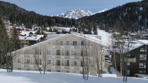 a large white building in the snow with a mountain at Residence Antares in Madonna di Campiglio