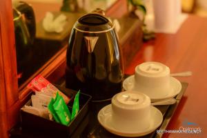a tea pot and two cups on a table at Seethawaka Regency in Avissawella