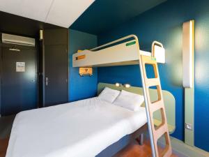 a bunk bed in a blue room with a ladder at ibis budget Mâcon Nord in Mâcon