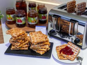 a display of waffles and jam on a counter with a toaster at Ibis Budget Fréjus Capitou in Fréjus