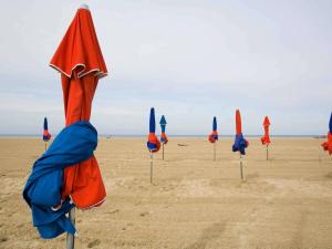 a row of closed umbrellas on the beach at Hotel Ibis Budget Deauville in Deauville