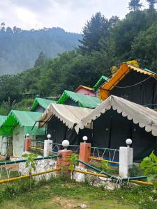 a group of buildings with trees in the background at Jalpa Camp Kasol in Kulu