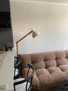 a living room with a couch and a lamp at Departamento en Maule, cerca Estadio Nacional y metro Ñuble in Santiago