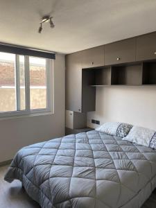 a bedroom with a large bed and a window at Departamento en Maule, cerca Estadio Nacional y metro Ñuble in Santiago