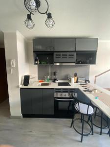 a kitchen with a stove and a counter with chairs at Departamento en Maule, cerca Estadio Nacional y metro Ñuble in Santiago