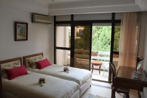 a bedroom with two beds and a desk and a balcony at Villa Sidi Bou Said in Sidi Bou Saïd