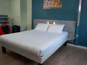 a bed with white sheets and pillows in a room at Ibis Budget Le Havre Les Docks in Le Havre