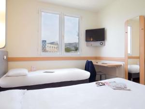a hotel room with two beds and a tv at ibis budget Aubagne Paluds Agora in Aubagne +79 photos