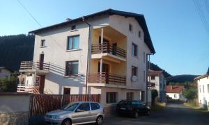 a building with two cars parked in front of it at Guest House Lorian in Madzhare