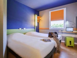 a room with two beds and a window at Ibis Budget Porte de Camargue in Saint-Martin-de-Crau
