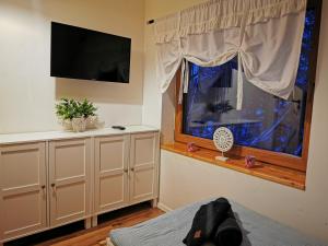 a bedroom with a tv and a window and a bed at Dom całoroczny Leśny Czar balia, sauna na 12 osób in Raków
