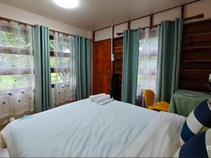 a bedroom with a white bed and green curtains at Payim farmstay in Ban Nam Khrai