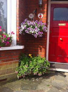 une porte rouge avec un bouquet de fleurs devant une maison dans l'établissement 38 Whitehall Road, à Harrow on the Hill