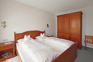 a bedroom with a large white bed with a wooden headboard at Gästehaus Schloss Kronburg in Kronburg