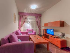 a living room with two purple couches and a tv at Porto Matrouh Apartments By Amer-Group in Marsa Matruh